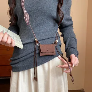 Dettaglio catena in vita in tessuto stile etnico con perle in legno e mini borsa pouch