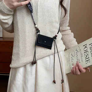 Dettaglio della catena in vita in stile etnico con sacchetto in tessuto e perle di legno.
