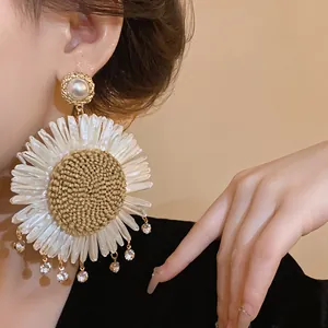 Detailansicht eines böhmischen Gänseblümchen-Ohrrings mit Stroh, Perlen und Kristallen.