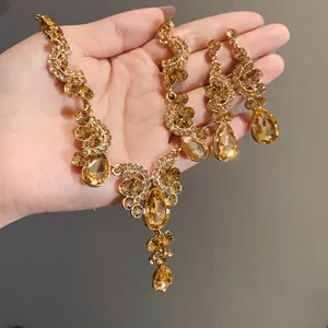 Close-up of the vintage gold jewelry set with amber teardrop crystals held in hand.
