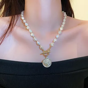 Elegant baroque pearl necklace with a vintage gold coin pendant shown on a model