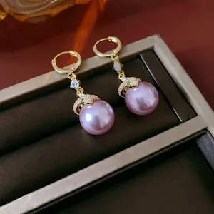Close-up detail of vintage gold-toned earrings with round purple pearls and zircons.