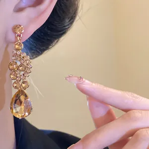 Close-up detail of vintage champagne crystal teardrop earrings being worn on a model's ear
