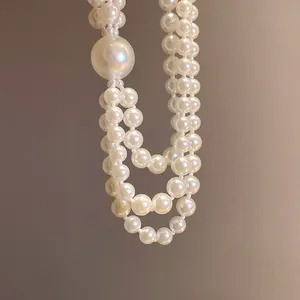 Close-up detail of an elegant multi-strand pearl necklace featuring a large central pearl design