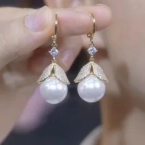 Close-up of elegant gold earrings with white pearls and sparkling cubic zirconia details
