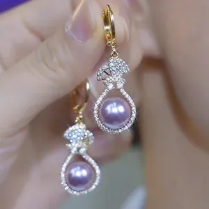 Detailed macro shot of elegant golden hoop earrings featuring zircon and purple pearl
