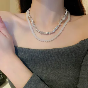 Close-up of double-layered baroque silver beads and white pearl necklace on neck.