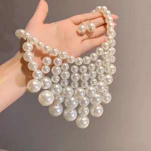 Close-up of layered pearl fringe necklace and earrings held in hand