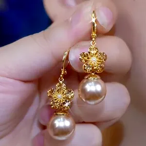 Close-up view of elegant gold flower earrings featuring large pinkish-beige artificial pearls