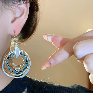 Elegante mehrlagige unregelmäßige runde Tropfenohrringe mit Metallfinish an einem Modell.