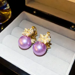 Detail view of purple pearl earrings with zircon flower accents in a grey jewelry box.