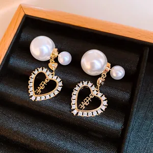 Macro shot of vintage gold heart earrings with white faux pearls and sparkling zirconia