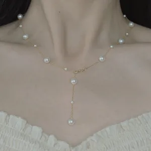 Elegant gold chain Y-shaped lariat necklace with white pearls shown on a female model.