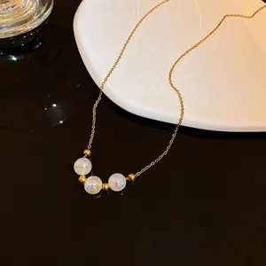 Detailed view of iridescent white beads and gold chain necklace on reflective surface