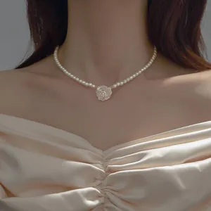 Elegant camellia flower pendant on a classic pearl necklace choker detail view