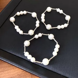 Set of three French vintage pearl necklaces with silver tube accents on black background