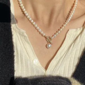 Close-up view of an elegant baroque pearl necklace with a golden OT buckle and pendant.