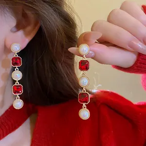 Detailed view of french vintage earrings featuring round pearls and red zircons.