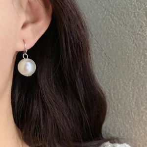 Close-up of elegant French vintage style large round white pearl drop earring on model