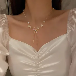 Elegant pearl necklace with crystal bow and tassel pendant shown on a model neck