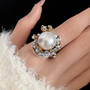 Detailed view of an elegant vintage floral pearl ring worn on a hand with a white sweater