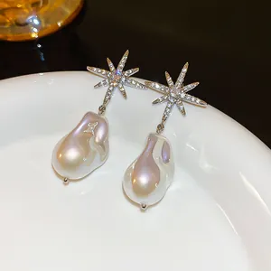 Macro detail of star-shaped zircon stud earrings with elegant baroque artificial pearl drops