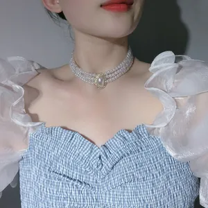 Close-up detail of three-strand pearl choker necklace with ornate vintage centerpiece