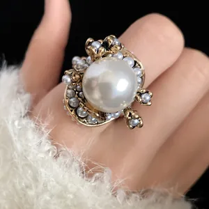 Detailed close-up of a vintage French pearl flower ring with antique gold finish on a hand