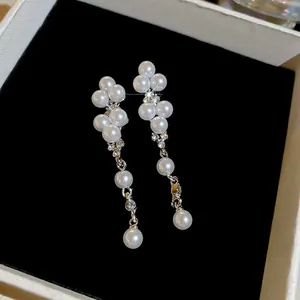 Detail view of elegant zirconia and round faux pearl drop earrings in a black box