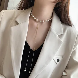Elegant Baroque pearl choker necklace featuring a delicate long drop pendant on a model