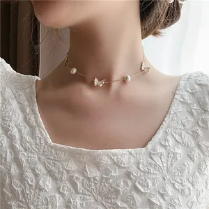 Elegant gold chain necklace featuring white butterfly charms and pearls on a model