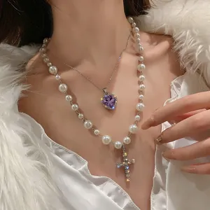Detail of a double-layer pearl necklace with purple heart and sparkling cross pendants