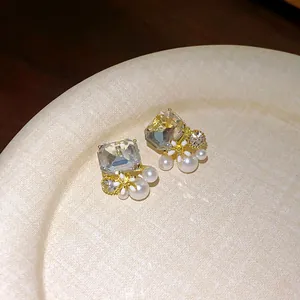 Detailed view of French retro earrings with clear zirconia, white flowers, and pearls