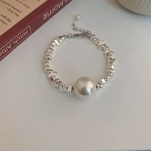 Detailed view of a minimalist silver bracelet featuring irregular beads and a large pearl