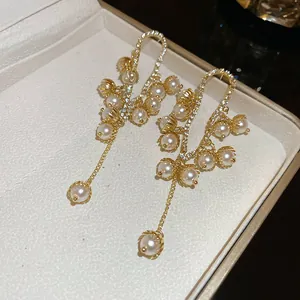 Detailed macro view of elegant gold-finish drop earrings with white pearls and zircons.