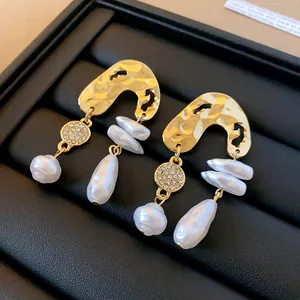 Macro view of French vintage earrings featuring gold hammered texture and baroque pearls