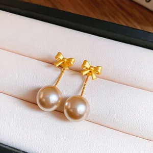 Detailed macro view of elegant gold bow stud earrings with champagne pearl drops.