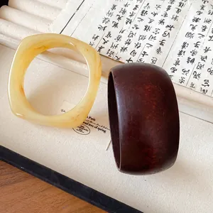 Gros plan d'un bracelet en résine marbrée et d'un large jonc en bois sur un plateau à bijoux.
