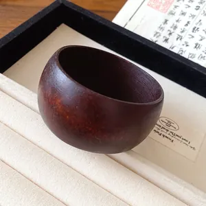 Gros plan d'un bracelet jonc épais en résine marron foncé rétro au fini bois