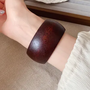 Gros plan d'un large bracelet en résine de style vintage avec texture bois marron foncé