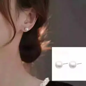 Close-up detail showing elegant white pearl stud earrings worn by a female model