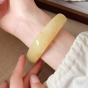 Gros plan d'un bracelet vintage en résine jaune ambre translucide porté sur un poignet