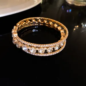 Primer plano detallado de un brazalete de oro de tres capas con circonitas brillantes