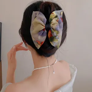 Gros plan d'une pince à cheveux à nœud floral sur un modèle avec un collier de perles