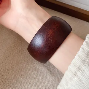 Détail d'un large bracelet vintage en résine marron foncé avec une texture imitation bois