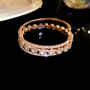 Detalle macro de brazalete abierto de tres capas en oro rosa con circonitas