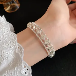 Vista detallada de un elegante brazalete de circonitas plateadas de tres filas en la muñeca
