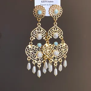 Primo piano di orecchini vintage in oro con smalto blu e gocce di perle pendenti
