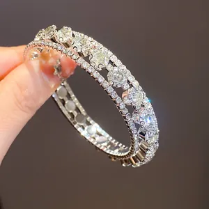 Primer plano de un lujoso brazalete abierto de tres filas de circonitas plateadas y brillantes