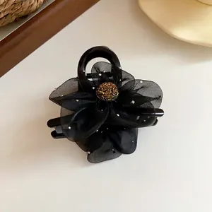 Pince à cheveux élégante avec fleur en tulle noir et centre doré scintillant.